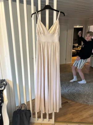 Balklänning - Beige, guldskimrande balklänning/ festklänning från Bubbleroom i storlek 34. Två fläckar, en fram och en bak. Knappt synbara pga fallet, inget man ser vid användning. Uppsydd men går att sprätta upp. Jag är 164 vid referens. Använd två gånger, än av mig och en av en tidigare säljare🤗💞