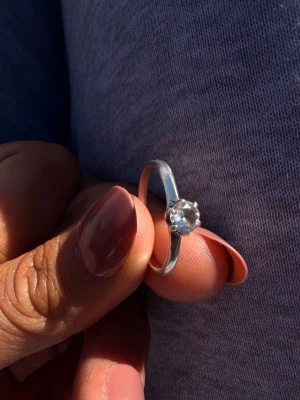 925 Silverring med klar sten i äkta silver  - Stilren silverring med en rund, klar sten i solitärfattning. 92.5% silver. Köptes i en guldbutik för ca 2 år sedan och fick den i present. Väldigt fin och elegant. Den är i använd skick och storleken är ca 19mm. Nypris:1500kr