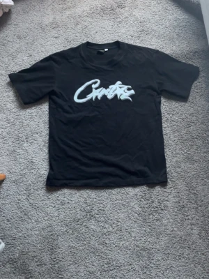Svart t-shirt med grafiskt tryck - Säljer en svart t-shirt från Crtxz med ett stort grafiskt tryck i vitt och ljusgrönt på bröstet. Klassisk rund hals och korta ärmar. Perfekt för dig som gillar streetwear och vill sticka ut med en unik design. Använd en gång bara den passar folk som är mellan 160-180 typ det beror på hur mycket du väger o sånt pris kan diskuteras (obs ej äkta)