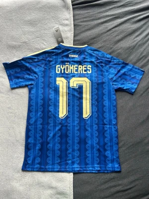 Gyökeres Sverige tröja 2026 - Säljer denna riktigt snygga Sverige tröjan inför VM 2026 med Gyökeres på ryggen. Den är helt ny med tagsen kvar. Storleken är Medium men kan passa S också. 🎯  - Storlek M  - Nyskick med tags  - Pris 499kr💰  Hör av er vid frågor eller bilder! ✅ 