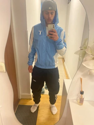 Malmö FF blå träningsjacka Puma - Säljer en snygg ljusblå träningsjacka från Puma med Malmö FF-logga på bröstet. Jackan har vita detaljer på ärmar och sidor, dragkedja och huva. Perfekt för fotboll eller träning, riktigt sportig look.