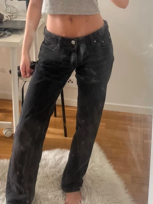 Svarta raka jeans - Säljer ett par svarta jeans med rak passform och låg midja. Jeansen har klassisk femficksdesign och stängs med knapp och dragkedja. Materialet är denim i bomull och de har en avslappnad look som passar till det mesta. Stil Arrow