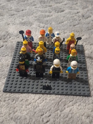 Samling "ÄKTA" LEGO minifigurer på platta - Säljer en samling med LEGO minifigurer placerade på en grå basplatta. Figurerna har olika yrken och utstyrslar, bland annat polis, riddare, byggarbetare och sjukvårdare. Flera har tillbehör som hjälmar, hattar och verktyg. Perfekt för dig som gillar LEGO och vill utöka din samling.
