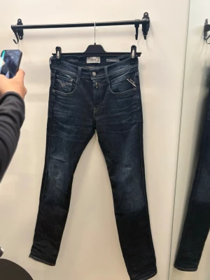 Replay Jeans  - Snygga mörkblå skinny jeans från Replay med klassisk femficksdesign och en cool dragkedjedetalj på ena fickan. Jeansen har en lätt tvättad look och smal passform som sitter tajt längs benen. Perfekta för en trendig och avslappnad stil.