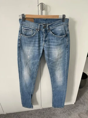 Ljusblå slim fit jeans från Dondup - Snygga ljusblå jeans från DunDop med slim fit passform och klassisk femficksdesign. Jeansen har slitningar och blekta partier för en trendig look samt detaljerade sömmar på bakfickorna. Perfekta för en avslappnad streetstyle.