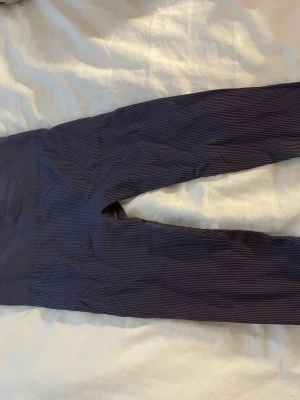 Svarta ribbade leggings - Säljer ett par svarta leggings med ribbad struktur och hög midja. De är stretchiga och sitter tight, perfekta till en avslappnad look. Materialet känns mjukt och följsamt, vilket gör dem riktigt bekväma att bära hela dagen. Passar till träningen