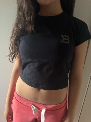 Svart croppad topp med öppen rygg Better boodies - Svart croppad topp med korta ärmar och en snygg öppen ryggdetalj. Toppen är från better boodies och är tillverkad i ett mjukt material som känns skönt mot huden. Perfekt för dig som gillar trendiga och bekväma plagg.