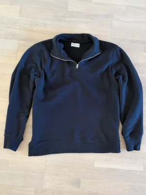 Mörkblå halvzip tröja These Glory Days - Säljer en mörkblå tröja från These Glory Days med halv dragkedja och ståkrage. Tröjan har ribbade muddar vid ärmslut och nederkant. 