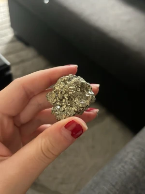Vacker pyrit - Säljer en riktigt fin pyrit i naturlig form på 31 gram. Stenen har en fantastisk metallisk glans som fångar ljuset på ett unikt sätt och ger ett exklusivt, nästan guldlikt utseende. Pyriten har en vacker kristallstruktur som gör den både dekorativ och intressant för samlare eller den som vill ha en naturlig inredningsdetalj med karaktär. Perfekt att ha i ett rum, på ett skrivbord eller i en kristallsamling.