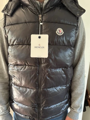 Svart Moncler dunväst - Ny svart Moncler dunväst med luva. Normal passform. NFC scannar, Hör av er vid frågor eller fler bilder!