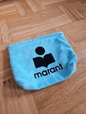 Blå corduroy necessär från Isabel Marant - Cool liten Isabel Maranr i ljusblå corduroy med svart Marant-logga på framsidan. Perfekt för att förvara småsaker eller använda som sminkväska. Mjuk och flexibel form, med tydlig ribbad struktur i materialet.