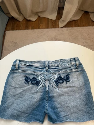 Blå jeansshorts med nitar Halobe - Blå vintage jeansshorts med slitna kanter och dekorativa nitar på fickorna. Dessa short är från 90-talet, men nästan aldrig använda. Jättesnygga!!!