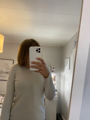 Beige stickad tröja med rund hals - Säljer en stilren beige stickad tröja med rund hals och långa ärmar. Tröjan har en enkel och klassisk design med ribbstickade muddar vid ärmslut och nederkant. Perfekt att matcha med jeans eller kjol för en clean look.