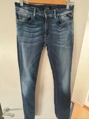 Blå slim jeans från Replay - Snygga blå slim fit jeans från Replay med klassisk femficksdesign. Jeansen har normal midja och är tillverkade i mjuk bomullsblandning med stretch för extra komfort. Perfekta för en trendig och avslappnad look. Pris kan diskuteras.