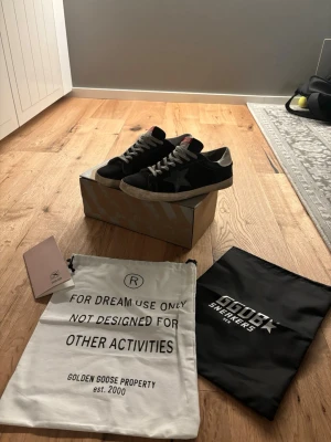 Golden goose skor - Mörk blåa sneakers från Golden Goose med vit sula, gråa skosnören och en ikonisk stjärna på sidan. Tungan har en röd detalj med logga och hälen är i silver. Skorna har en vintage-look och levereras med originalpåse och box.