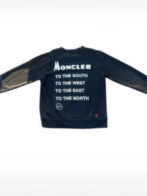 Svart sweatshirt från Moncler - Cool svart sweatshirt från Moncler med vit text på framsidan: 'TO THE SOUTH, TO THE WEST, TO THE EAST, TO THE NORTH'. Tröjan har rund halsringning och långa ärmar. Perfekt för en avslappnad streetstyle-look.