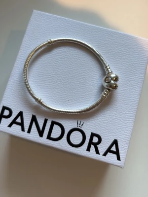 Pandora silverarmband med hjärtformad lås storlek 16 - Snyggt armband från Pandora i äkta silver med ett hjärtformat lås där Pandora-loggan är ingraverad. Köptes 1 vecka sen som present till mors dag men den var inte rätt storlek.. tappade bort kvittot och kan därmed inte lämna tillbaks den och därför säljer den. ALDRIG ANVÄND 