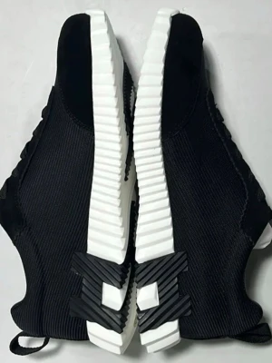 Svarta sneakers   - Stilrena svarta sneakers från  med vit, räfflad sula och ovandel i mesh och mockaimitation. Skorna har svarta skosnören och en låg profil som passar perfekt till streetwear. Snygga detaljer på sulan och dragflikar bak för enkel påtagning.
