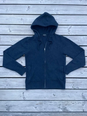 Mörkblå hoodie från Firefly - Mysig mörkblå hoodie från Firefly med dragkedja framtill och två fickor. Tillverkad i ett stickat material som känns både varmt och skönt. Riktigt fet zip up, fråga vid minsta lilla fundering👍 så tar vi det därifrån!! 