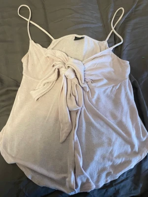 Linne med Knut - Ljusrosa linne med tunna axelband och knytdetalj framtill. Mjukt och bekvämt material med fin passform, perfekt till sommaren eller att styla till vardags. Fint skick och säljs då det inte används längre.