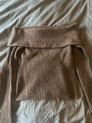 Brun off shoulder stickad tröja - Säljer en brun ribbstickad off shoulder-tröja med bred krage. Tröjan har långa ärmar och är gjord i ett mjukt, mysigt material som passar perfekt till kyligare dagar. Ser mer använd ut än vad den är🥰 är i mycket bra skick 