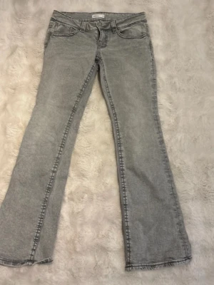 Grå bootcut jeans från Perfect Jeans - Snygga grå bootcut jeans från Perfect Jeans med klassisk femficksmodell och normalhög midja. Jeansen har en lätt tvättad look och är tillverkade i mjukt denimtyg. Perfekta för dig som gillar en avslappnad men trendig stil.