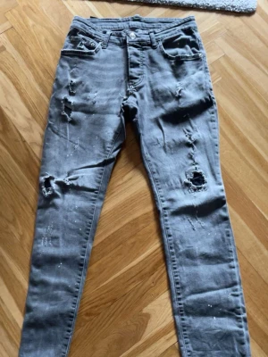 Grå slitna jeans från DSQ - Säljer ett par grå fett snygga och sköna jeans från DSQ (DSQAURED) knappgylf och broderad logga på bakfickan. Tillverkade i denim. Och såklart äkta. Priset kan diskuteras 