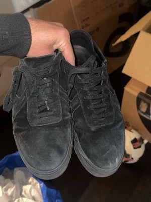Arigatos - Stilrena svarta sneakers i mocka med klassisk låg siluett och matchande svarta skosnören. Snygg minimalistisk design som passar till det mesta. Yttersulan är också svart för en clean look.