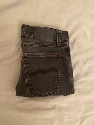  Nudie Jeans - Snygga svarta jeans från Nudie Jeans med klassisk femficksdesign och svarta sömmar på bakfickorna. Jeansen är verkligen i toppen skick och bara använda får par ggr. Hör av er vid minsta lilla fråga 🫡