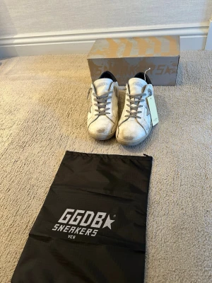 Golden goose  - Säljer ett par  vita Golden goose sneakers! Skorna är i helt okej skick. ✅ Dock saknas orginal sulan eftersom den gick sönder och jag slängde den. Det är helt enkelt bara att lägga i en annan sula vilket även kan göra skorna mer bekväma, också därav priset. Skorna är också lite stora i storleken så passar även 42. OBS! Priset är ej hugget i sten, skriv gärna vid minsta lilla intresse! 
