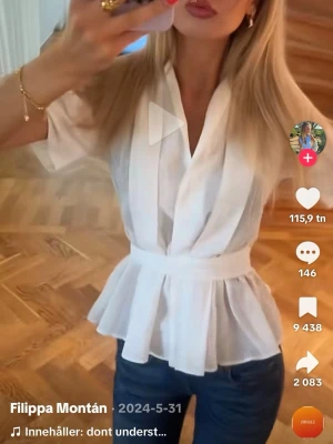 Vit blus Zara - Stilren vit omlottblus med korta ärmar och markerad midja. Blusen har v-ringning och ett lätt, luftigt tyg som ger en feminin siluett. Perfekt att matcha med jeans eller kjol för en trendig look.