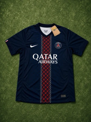 PSG matchtröja Nike mörkblå - Snygg mörkblå PSG matchtröja från Nike med röd och vit detalj längs mitten, klubbmärke på bröstet och Qatar Airways som sponsortryck. Perfekt för fotbollsträning eller för att se extra fräsch ut inför sommaren.