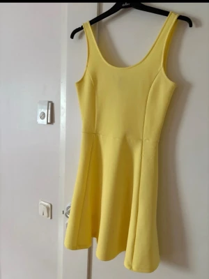 Gul ärmlös klänning med vidd - Snygg gul klänning med ärmlös design och rundad halsringning. Kommer tyvärr inte till användning 