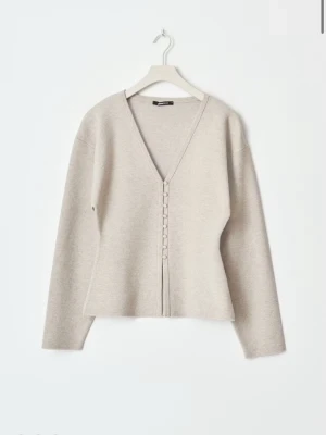 Beige kofta med knappar från Gina  - Stilren beige kofta från Gina med djup V-ringning och dekorativa knappar framtill. Koftan har lång ärm och är tillverkad i ett mjukt, stickat material som ger en avslappnad men snygg look.