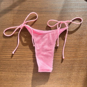 Rosa bikiniunderdel från PrettyLittleThing - Söt rosa bikiniunderdel från PrettyLittleThing med knyt i sidorna. Modellen har en ribbad struktur och är tillverkad i stretchigt material som sitter snyggt på kroppen. Perfekt för strandhäng eller poolparty!