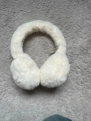 Vita fluffiga öronmuffar från ONLY - Supermjuka och fluffiga vita öronmuffar från ONLY. Perfekta för att hålla öronen varma under kalla dagar. Tillverkade i fuskpäls för en mysig känsla och snygg look. Snygg accessoar som lyfter vinterstilen.