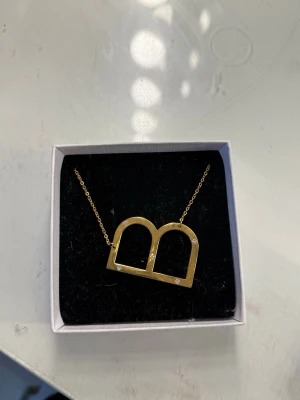 Guldigt halsband från ioaku - Super fint B halsband från IOAKU. Den har aldrig använts förutom att jag provat den på. Original pris 498
