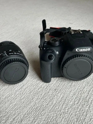 Canon systemkamera med 18-55mm objektiv - Säljer en svart Canon systemkamera tillsammans med ett Canon EF-S 18-55mm objektiv. Kameran har en klassisk design med greppvänligt handtag och tydliga reglage. Objektivet är kompakt och passar perfekt för både vardagsfoto och resor. I bra skick och säljer endast då den ej kommer till användning. 