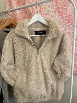 Beige/kräm teddyjacka från Vera Moda - Mysig beige teddyjacka från Vera Moda. Jackan har lång ärm, en stor ficka på framsidan och en half zip-dragkedja för att hålla inne värmen eller vädra. Bred mudd/band nertill som är stretchigt. Håller värmen bra och är super gosig! Storlek S och säljer eftersom den är för liten på mig. Inga defekter, sparsamt använd och endast maskintvättad en gång nu innan den säljs. 