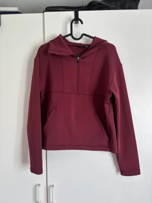 Vinröd träningshoodie från New Apparel🫶🏻 - Säljer en vinröd träningshoodie från New Apparel i storlek S (36/38). Hoodien har halv dragkedja framtill, stor huva och en magficka. Tillverkad i ett mjukt och stretchigt material som känns skönt mot huden. Perfekt för träning🤍