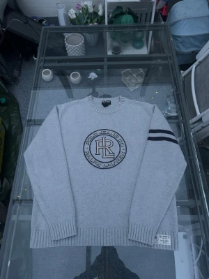 Vintage Polo Jeans Co Ralph Lauren Knit L - Riktigt clean vintage Polo Jeans Co Ralph Lauren stickad tröja i ljusgrå färg. Storlek L med sjukt snygg oversized/casual fit. Stor RL-logo framtill och stripe-detalj på ärmen som ger riktig 90s/Y2K vibe. 100% cotton med tung och skön kvalitet. Väldigt bra skick och perfekt för både streetwear, old money och clean outfits. Sjukt enkel att matcha med jeans, cargos eller shorts.  📏 Size L 🎨 Light grey 🧵 100% cotton ✨ Väldigt bra skick
