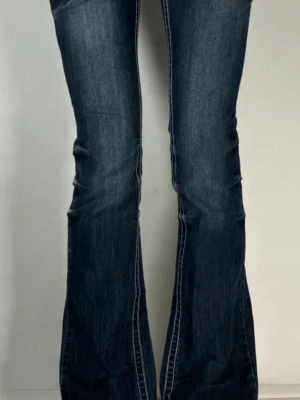 Mörkblå bootcut jeans med detaljer - Säljer ett par mörkblå bootcut jeans med snygga slitningar och markerade sömmar. Jeansen har en klassisk femficksmodell. Nypris:1300kr.                                                                Endast använda få gånger, inga tecken på användning 