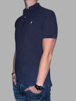 Mörkblå pikétröja från Ralph Lauren - 🔹 Märke: Ralph Lauren 🔹 Modell: Pikétröja  🔹 Storlek: M 🔹 Färg: Mörkblå 🔹 Skick: Fint skick, lite sliten i sömmarna men inget som syns vid användning. 🔹 Passform: Classic fit 🔹 Pris: 349kr  ✅ 100% äkta ✅ Snabb frakt ✅ Fler bilder/video finns vid intresse ✅ Stilren och lättmatchad