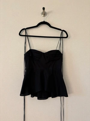 Svart peplum korsettopp från Zara - Snygg svart korsettopp med peplumvolang och tunna axelband. Aldrig använd så I jättebra skick❣️