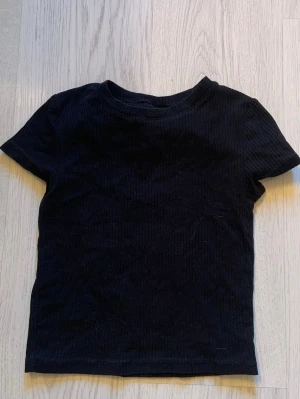 Svart ribbad t-shirt från H&M - En svart ribbad t-shirt från H&M som har korta ärmar. För liten för mig. 
