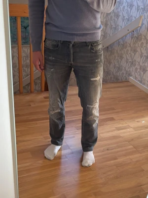 Gråa Replay Jeans - Säljer ett par Replay jeans i grå wash med slitna detaljer. Modellen på jeansen är Grover. Använda men fortfarande i bra skick utan större defekter. Passar till det mesta.  OBS! Storlek 30/32 från början men upplagda hos skräddare, så de passar mer som 30/29 i längden. Hör av dig frågor eller fler bilder✌️
