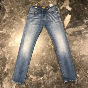 Ljusblå slim fit jeans från Jack & Jones - Snygga ljusblå slim fit jeans från Jack & Jones med klassisk femficksdesign och diskreta slitningar framtill. Jeansen har normal midja och är tillverkade i stretchigt denim för en bekväm passform.