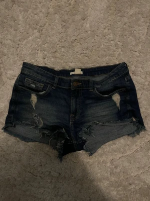Lågmidjade jeansshorts  - Lågmidjade jeansshorts med hål i ifrån hm. Kvaliteten är som på bilden då bilden är nytagen. Väldigt fina och säljer pga för små❤️