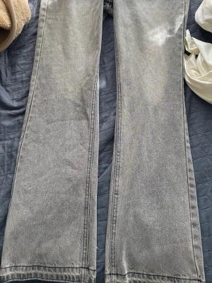 Grå raka jeans med vintagekänsla - Säljer ett par grå jeans med rak passform och klassisk femficksdesign. Jeansen har en snygg tvättad look som ger en vintage vibe och är tillverkade i denim. Perfekta för dig som gillar en avslappnad och stilren stil.