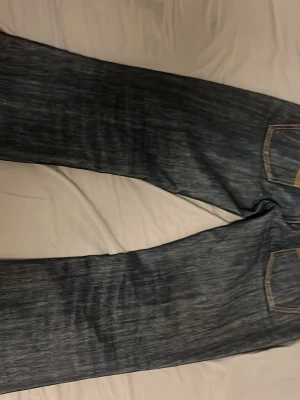 Mörkblå raka jeans från nudie  - Säljer ett par mörkblå jeans med raka ben och klassiska kontrastsömmar. Jeansen har fem fickor och är tillverkade i kraftigt denimtyg. Perfekta för dig som gillar en tidlös och enkel stil. Modellen på nudie jeansen är bootcut ola med storleken 30/32